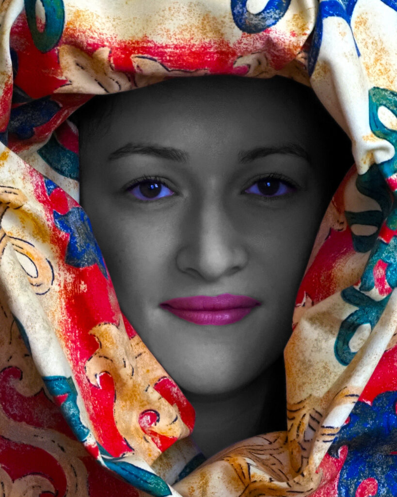 Portrait of a woman. Her head surrounded by multi-coloured fabric.