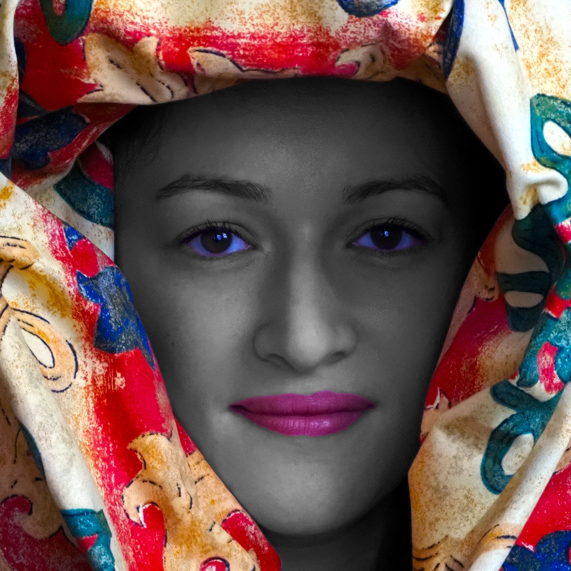 Portrait of a woman. Her head surrounded by multi-coloured fabric. Her skin monochrome. The whites of her eyes now blue. Her lips bright pink.