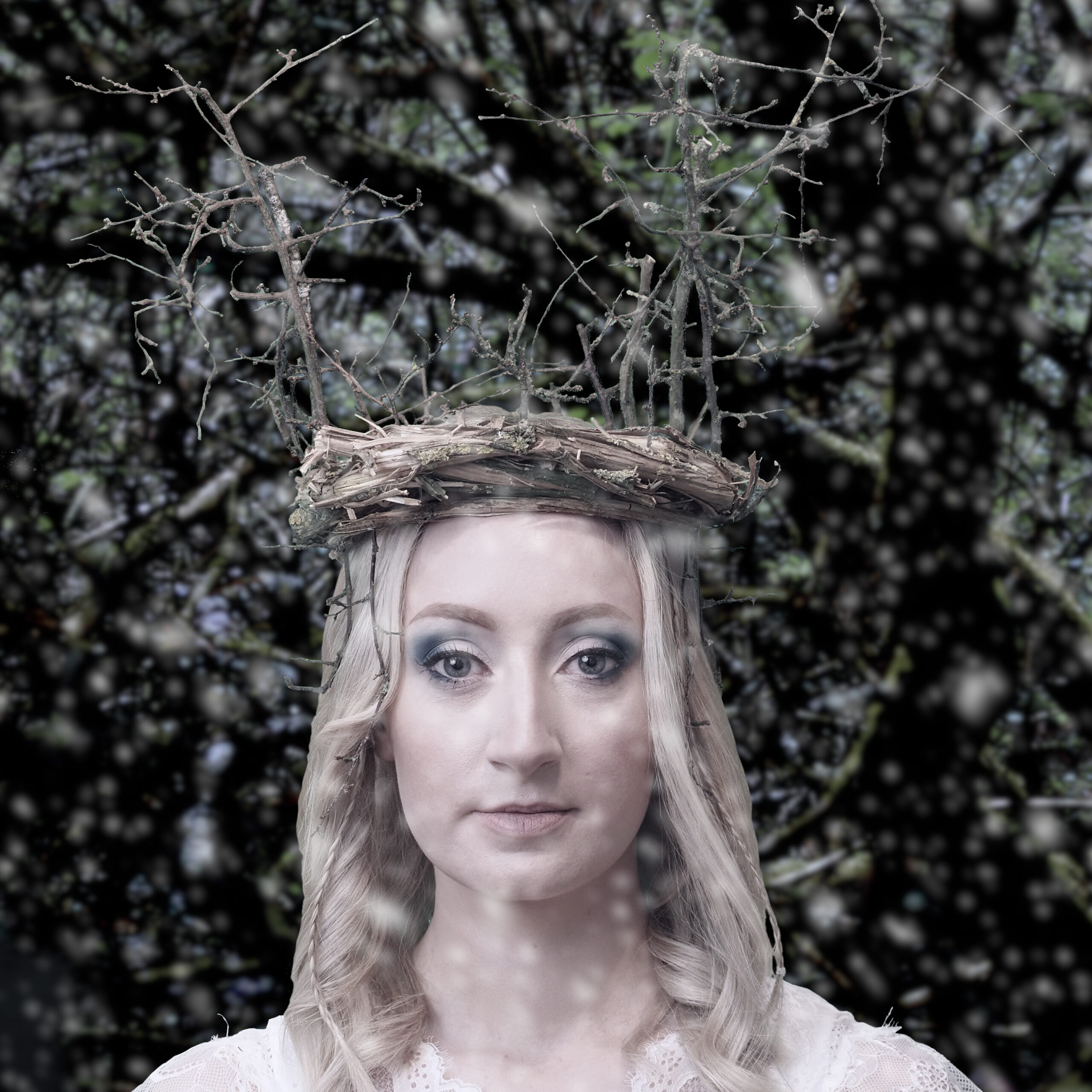 Creative portrait of a young woman with a crown of twigs. Wintery background with falling snow.